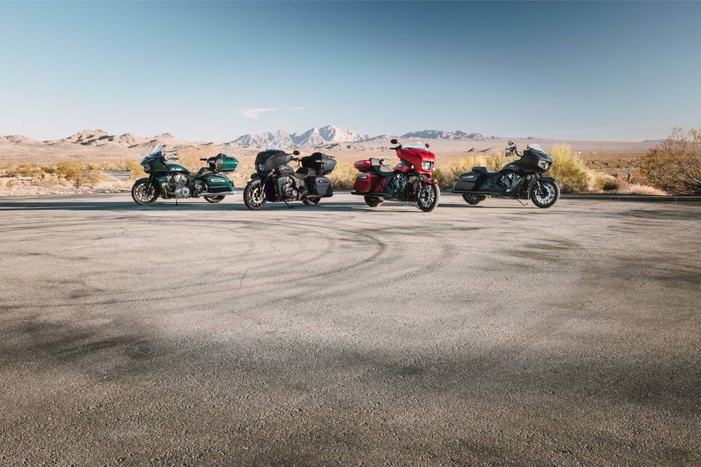 Four Indian Motorcycle touring models lined up on an open desert road with mountains in the distance