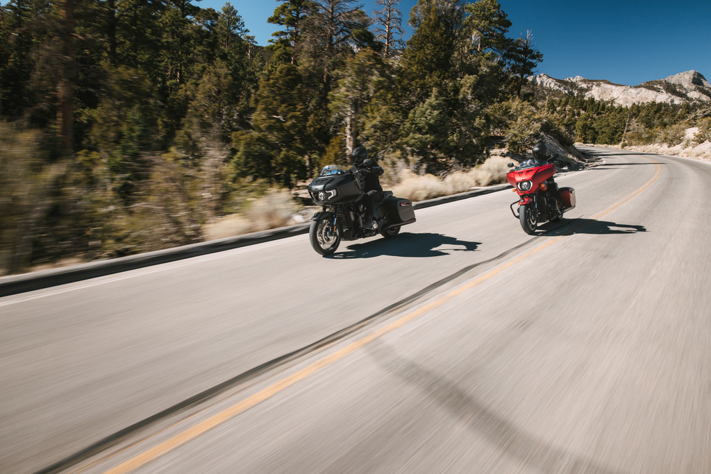 Two riders on black and red Indian Motorcycle touring bikes riding a winding mountain road